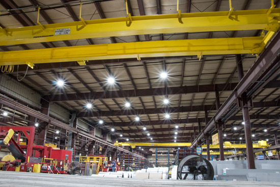Round shaped LED UFO High Bay Lights illuminating a large warehouse space filled with construction equipment